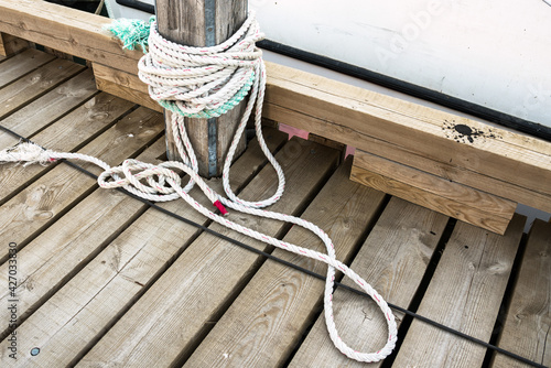 Close up of a nautical rope tied up to a mooring post on a wooden jetty photo