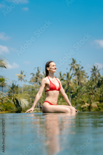 Woman in tropical vacation sitting in the water of pool