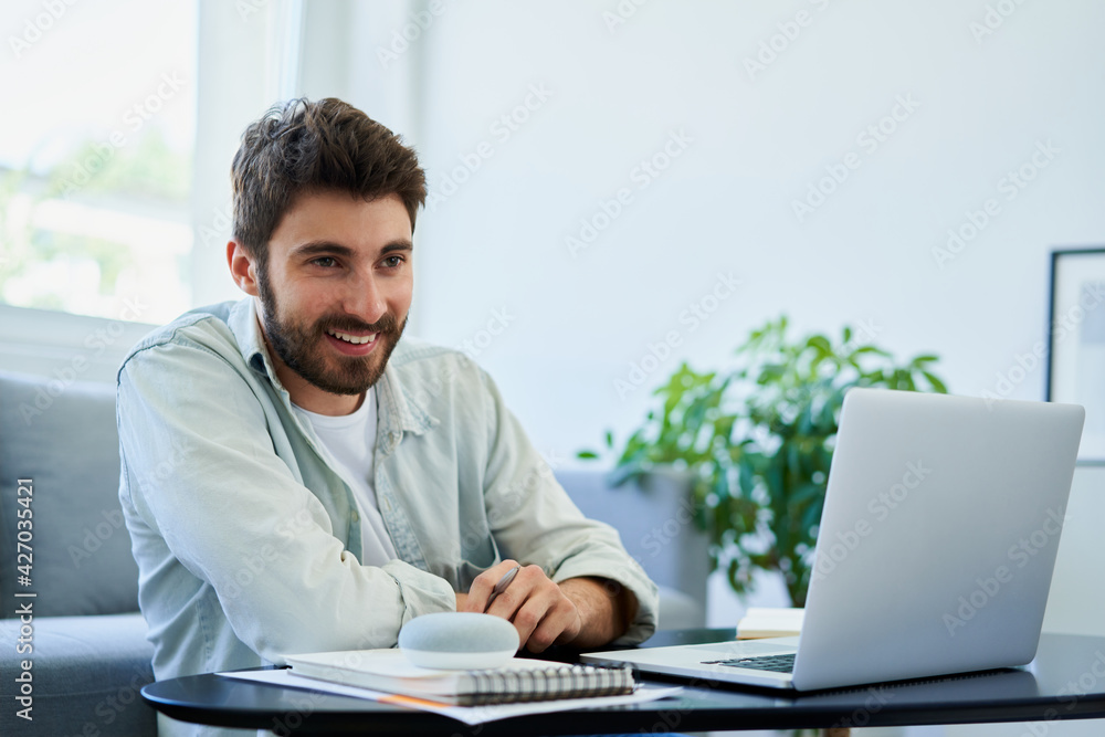 Happy young man using smart assistant speaker while working at home Happy young man using smart assistant speaker while working at home