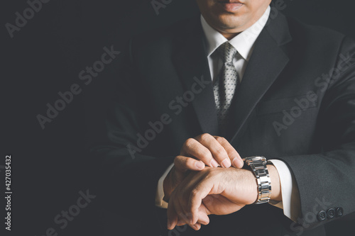 Businessman watching his wrist watch and checking time