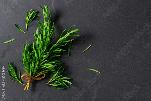 Branch of fresh rosemary on black table background, herb concept
