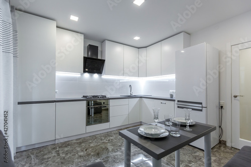 Interior photo  modern kitchen  in light white tones  with black marble tiles on the floor  placed in a small apartment