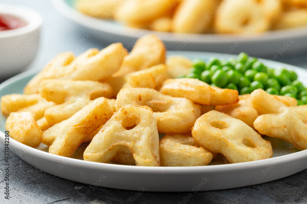 Letters potato fries snack with green peas and ketchup on plate. party food Letters potato fries snack with green peas and ketchup on plate. party food