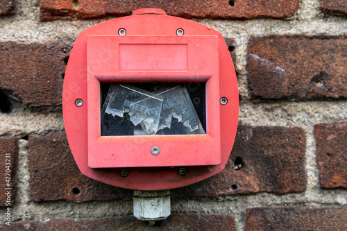 Brick wall with hand fire alarm with broken glass