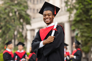 Cheerful african american guy in graduation costume
