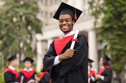 Cheerful african american guy in graduation costume photo