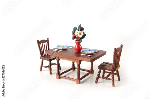 dollhouse interior - served dining table with a bowl with flowers isolated on white background