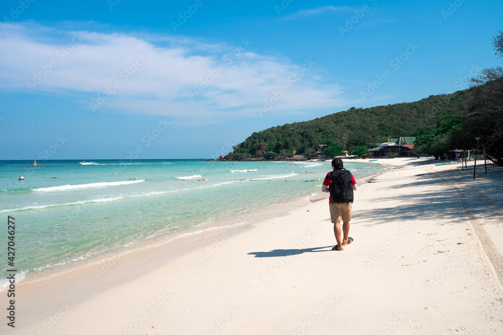 clear blue sea white sand beach in clear sky day on mountain island with backpacker man  walking on sand, Thian beach at Koh Larn island, travel destination in Chonburi, Thailand