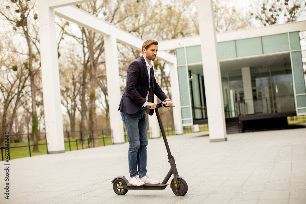 Young business man in a casual clothes riding an electric scooter by an office building on a business meeting Young business man in a casual clothes riding an electric scooter by an office building on a business meeting