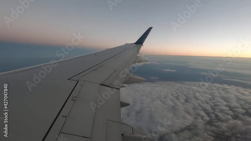 Cloudy sky view from the window of a plane with the wing in the view.  photo