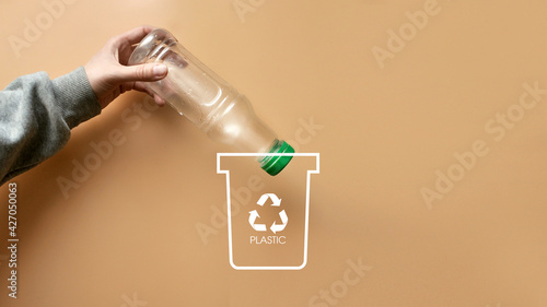 A man throws a plastic bottle into a dumpster .Sorting and recycling of garbage photo