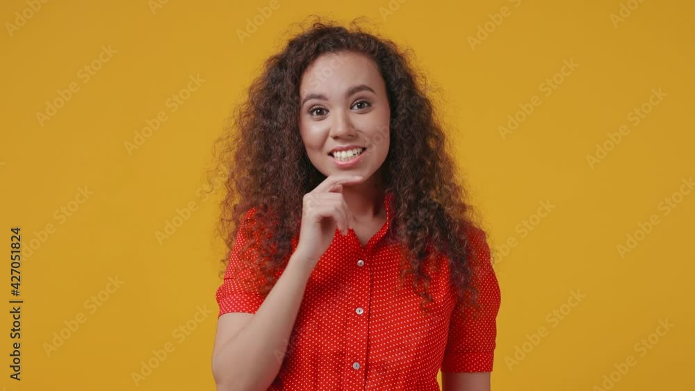 Pensive insighted smart young african american woman 20s years old in red dotted shirt posing isolated on yellow background studio. People lifestyle concept. Hold index finger up with great new idea Pensive insighted smart young african american woman 20s years old in red dotted shirt posing isolated on yellow background studio. People lifestyle concept. Hold index finger up with great new idea