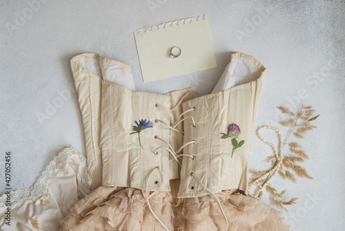 flat lay: beige vintage style corset and lace skirt, graceful ring photo