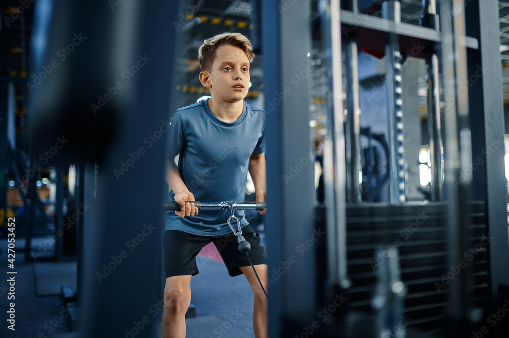 Boy on exercise machine, active training in gym Boy on exercise machine, active training in gym