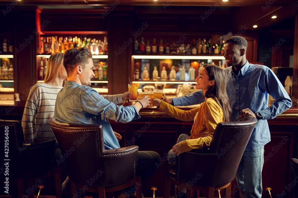 Four cheerful friends drinks beer in bar Four cheerful friends drinks beer in bar