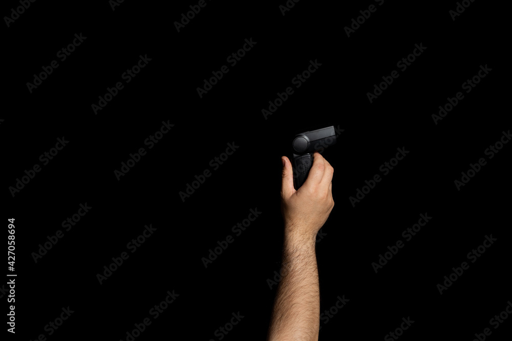 Raised man's hand holding a hand flash isolated on a black studio background Raised man's hand holding a hand flash isolated on a black studio background