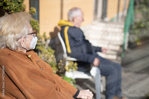 Elderly man and woman waiting outdoor to receive Covid-19 Vaccine, thinking about consequences