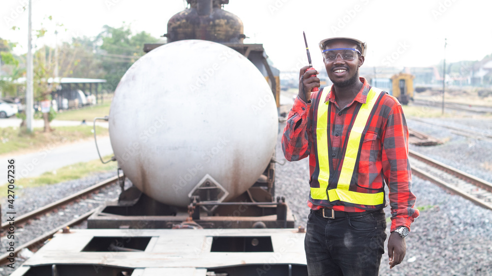 African man engineer holding radio communication or walkie talkie and standing on the train African man engineer holding radio communication or walkie talkie and standing on the train