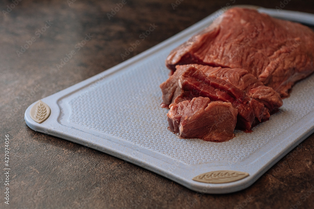 Raw beef meat on cutting board on the dark background