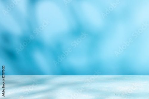 Abstract shadow on table top and blue wall background. Blurred backdrop with copy space.