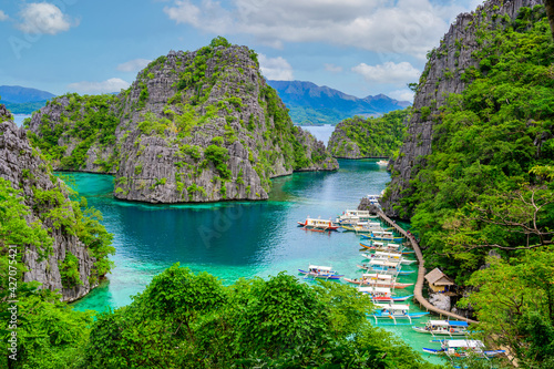 Blue crystal water in paradise Bay with boats on the wooden pier at Kayangan Lake in Coron island, Palawan, Philippines. photo