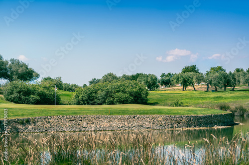 Golf course green with water hazard and stone wall