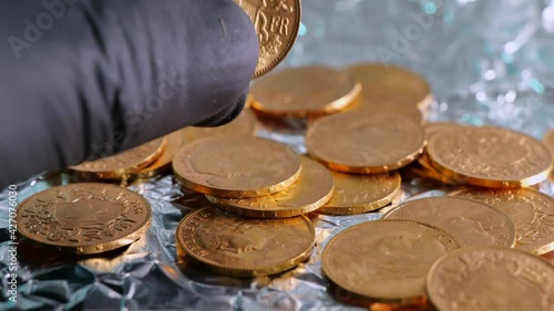 Hand with gloves checking shiny golden 20 swiss francs vreneli coins. Close up shot. photo