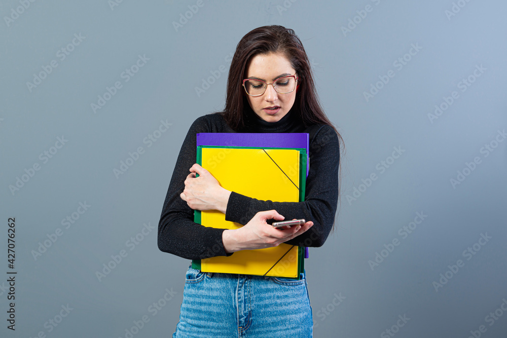 female with smartphone holding a colorfuls folders with documents, isolated on dark background