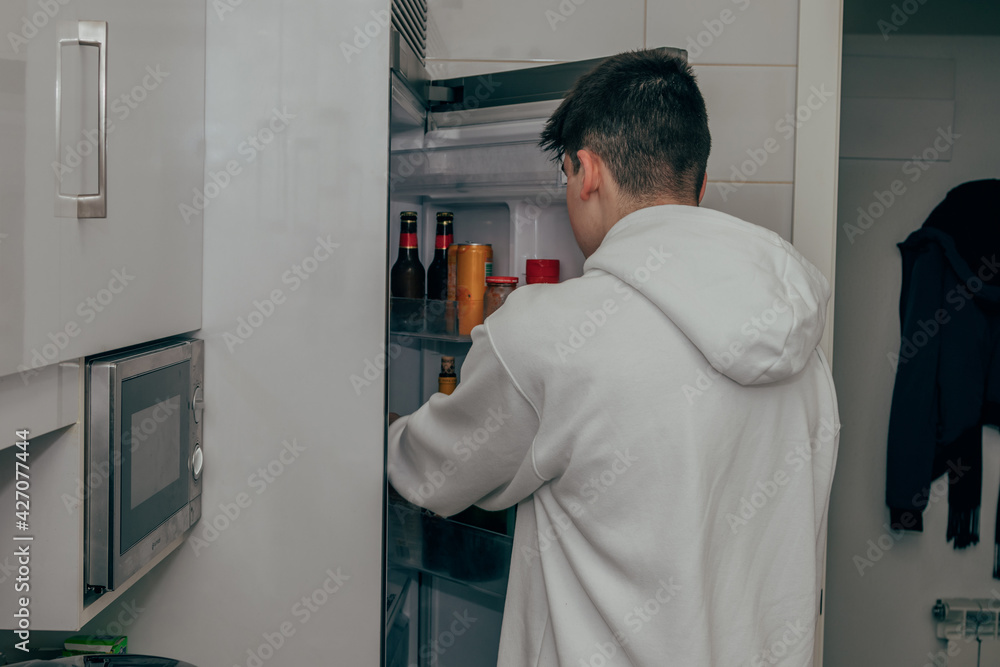 young teenager in the kitchen opening the fridge