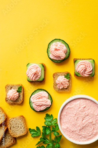 A bowl with tarama and crostini or taramasalata canape on the yellow background, top view with copy space