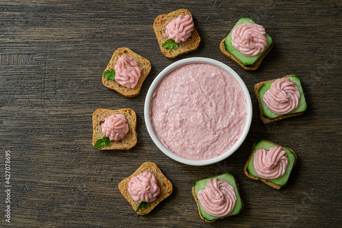 Different toasts with tarama around a white bowl with taramasalata on a dark wooden table, top view photo
