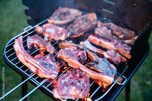 Grilled lamb chops. Meat cooking on the barbecue with burning embers. Preparing grilled meat on the garden barbecue.