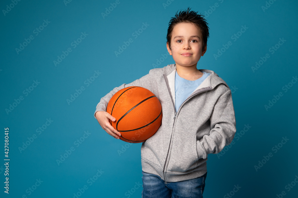 Portrait of an adorable sporty child holding a ball for playing basketball in hand Portrait of an adorable sporty child holding a ball for playing basketball in hand