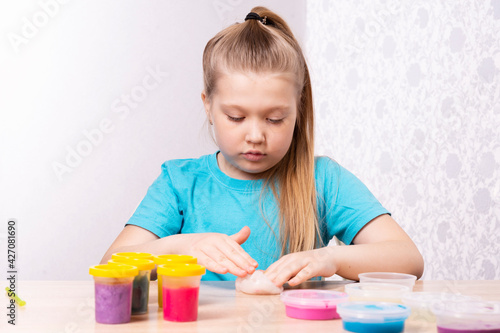 The blonde-haired child is playing with mucus. Little beautiful caucasian girl is playing with many slugs. Play Slime Toy