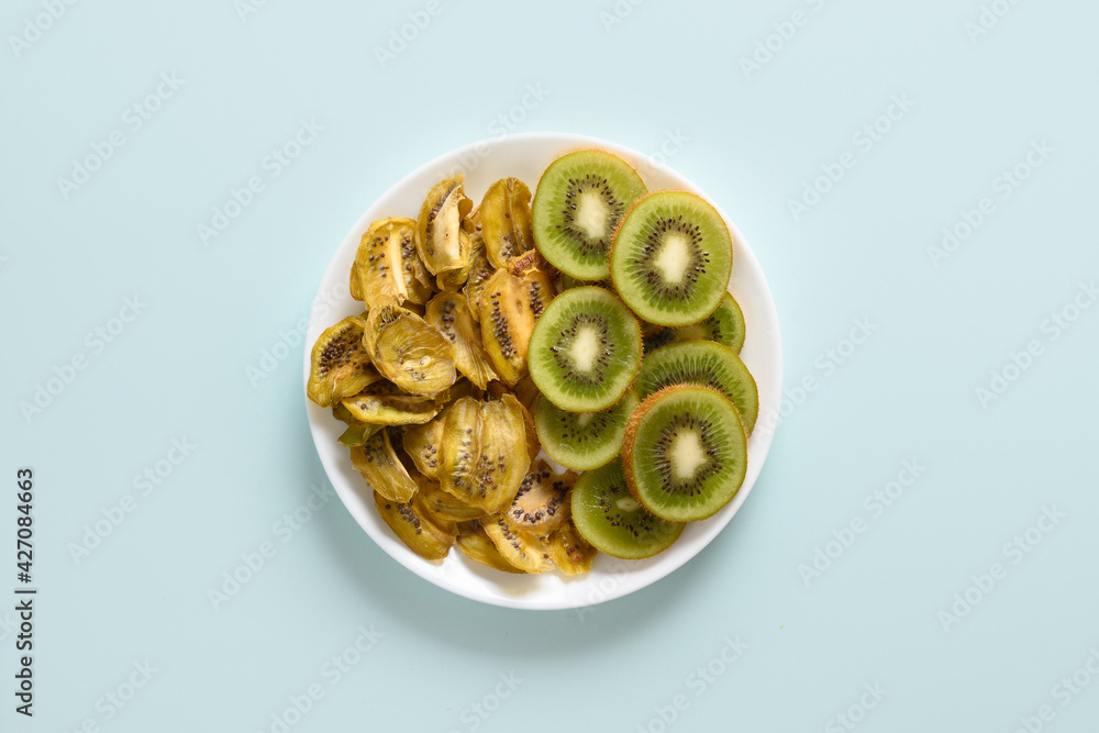 Sliced fresh and dried fruits kiwi chips on blue background, home drying. Snack vegan free sugar food. View from above. Sliced fresh and dried fruits kiwi chips on blue background, home drying. Snack vegan free sugar food. View from above.