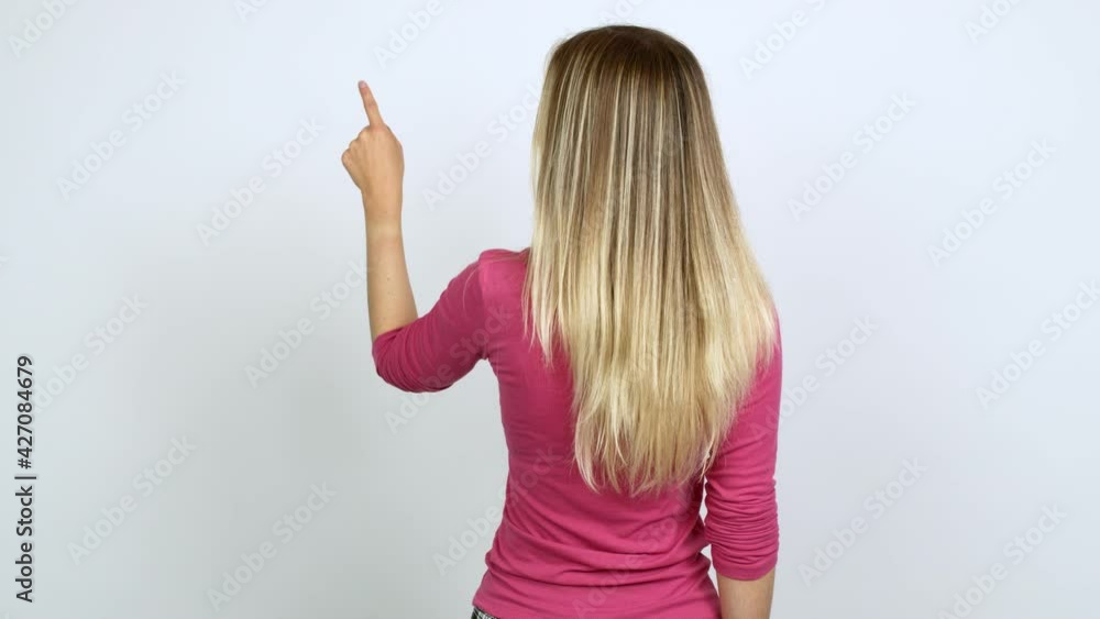 Young woman pointing back with the index finger over isolated background Young woman pointing back with the index finger over isolated background