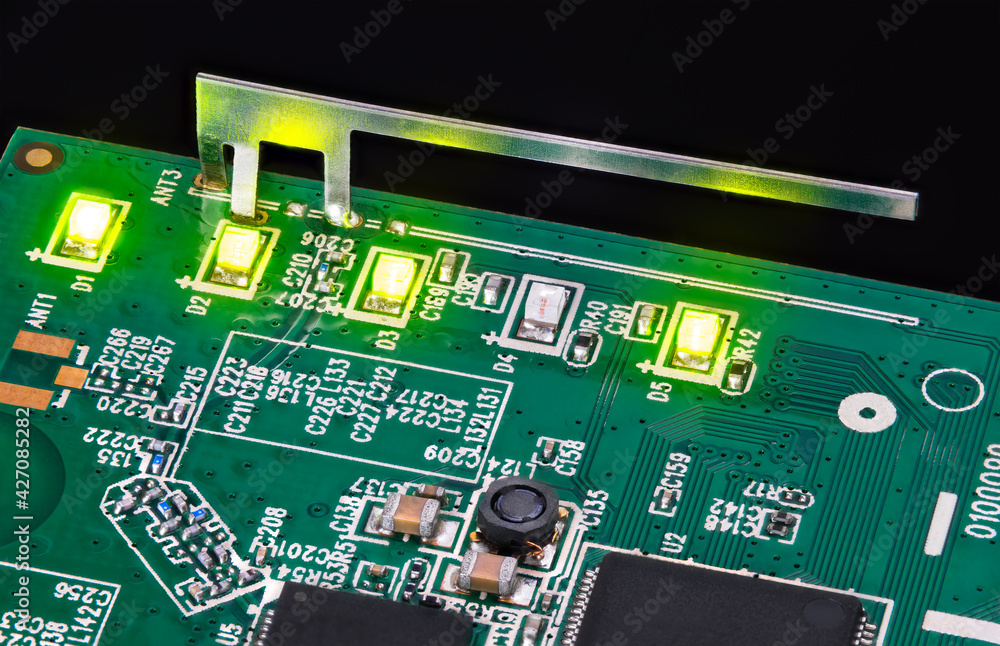 Small internal wifi antenna and shining LED lights embedded on circuit board.  Light-emitting diodes, capacitors and inductor in green PCB detail with  surface-mount technology of electronic components. Stock Photo | Adobe Stock