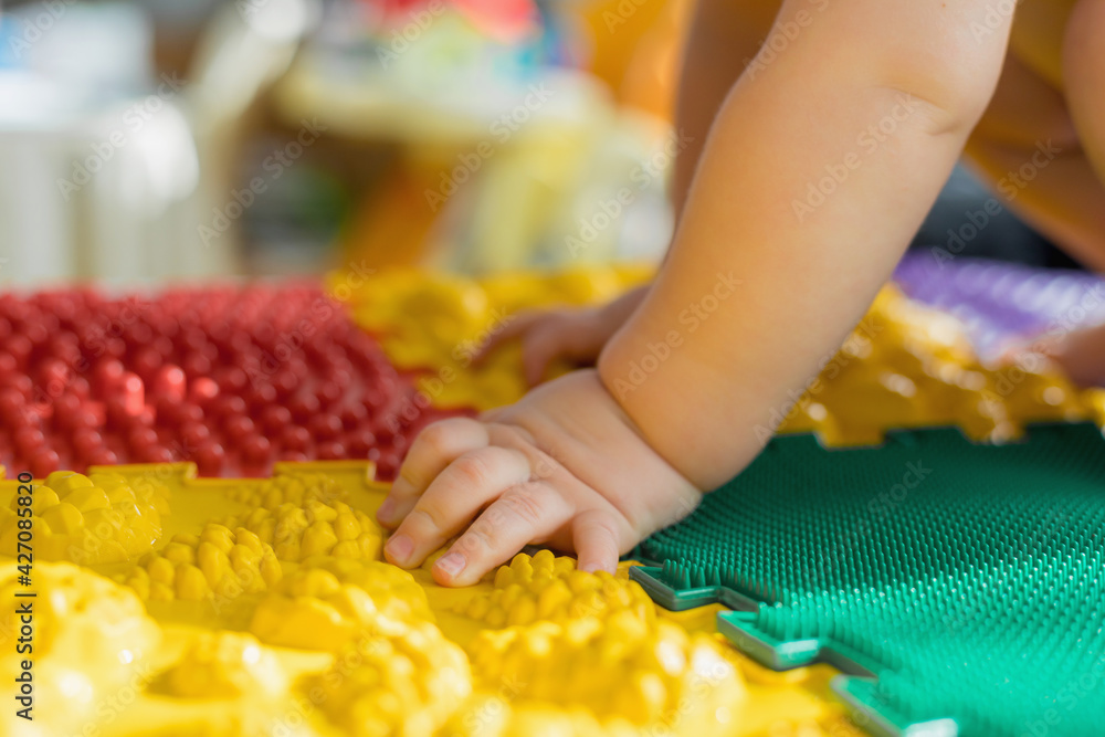 The kid walks barefoot on multi-colored massage rugs. The kid walks barefoot on multi-colored massage rugs.