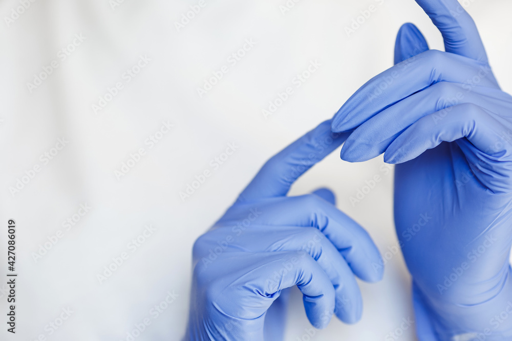 Hand wears a protective glove for cleaning or tidying. Female hand putting on latex glove isolated on white background.