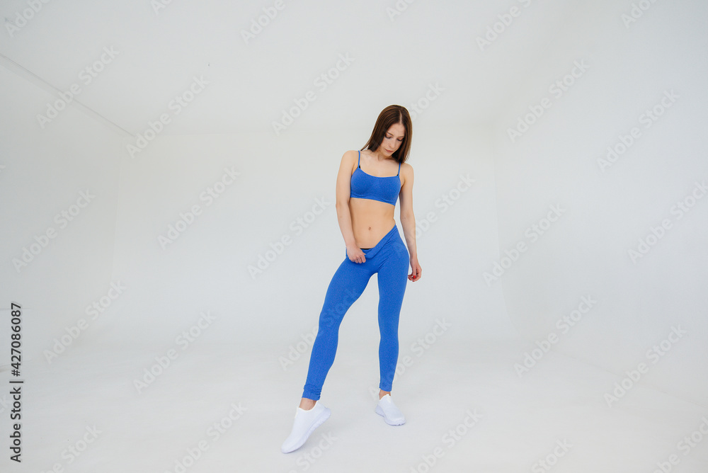 Sexy young girl performs sports exercises on a white background. Fitness, healthy lifestyle Sexy young girl performs sports exercises on a white background. Fitness, healthy lifestyle