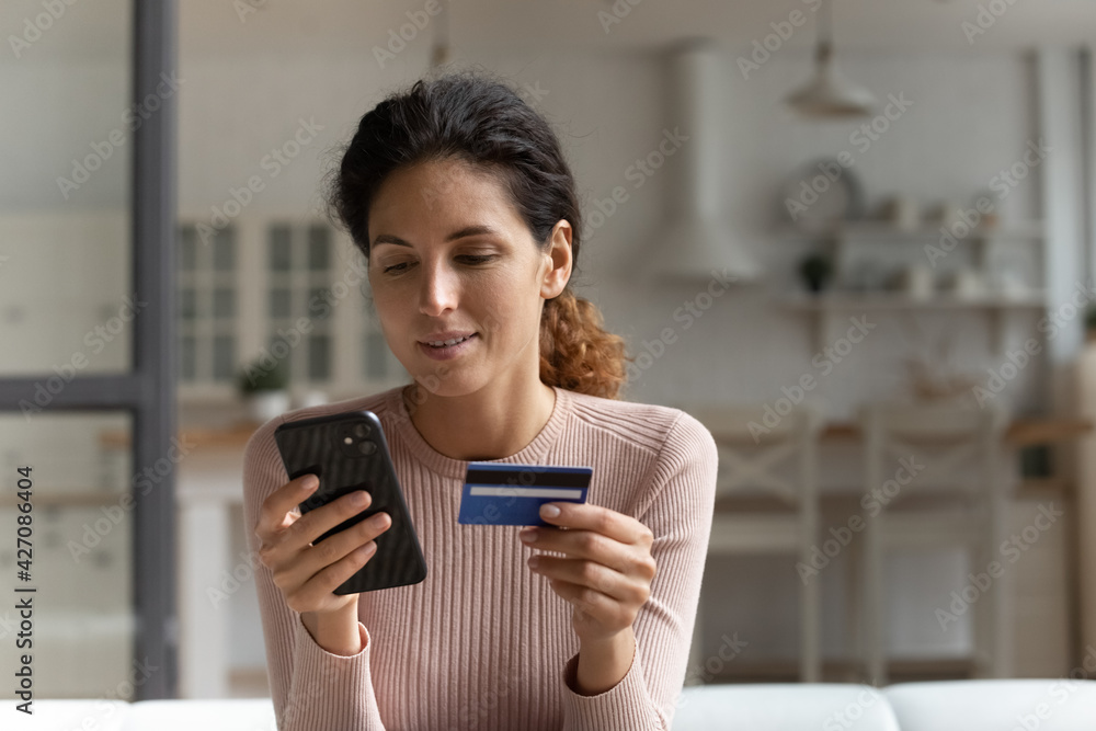 Focused concentrated millennial latina female using mobile telephone to make easy safe payment online in electronic bank system. Young lady client spend money from credit card in virtual shop via cell Focused concentrated millennial latina female using mobile telephone to make easy safe payment online in electronic bank system. Young lady client spend money from credit card in virtual shop via cell