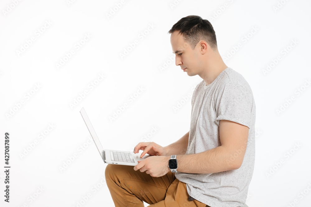 a man sits and holds an open computer on a white background a man sits and holds an open computer on a white background