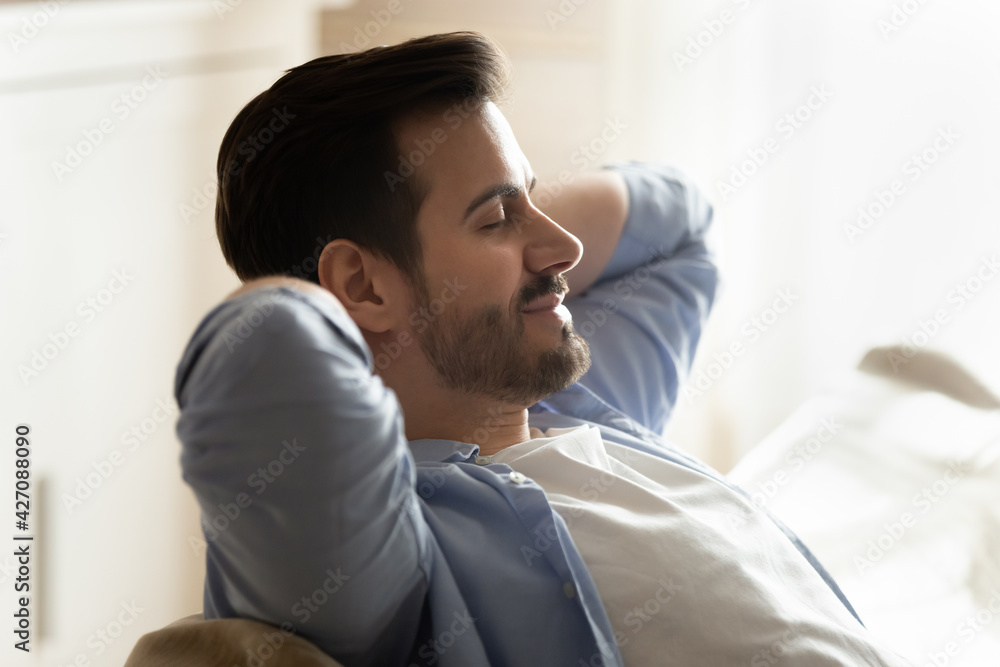 Young Caucasian man sit relax on couch breathe fresh ventilated condition air at home. Calm millennial male rest on sofa sleep or take nap, relieve negative emotions. Stress free concept. Young Caucasian man sit relax on couch breathe fresh ventilated condition air at home. Calm millennial male rest on sofa sleep or take nap, relieve negative emotions. Stress free concept.