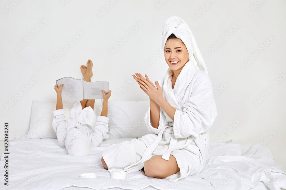 mother in white bathrobes and towels apply cream on hands mother in white bathrobes and towels apply cream on hands