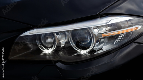 Headlights of black modern car close up.