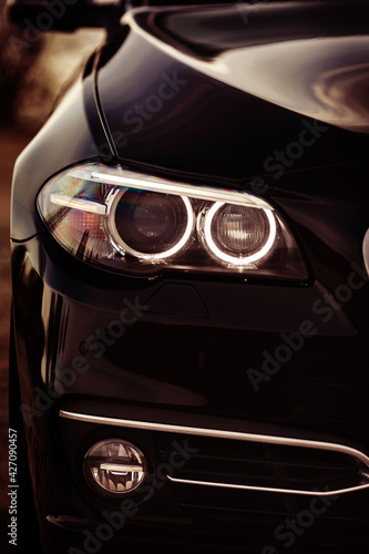 Modern car headlights close up. Prestigious auto wallpaper. © kucheruk