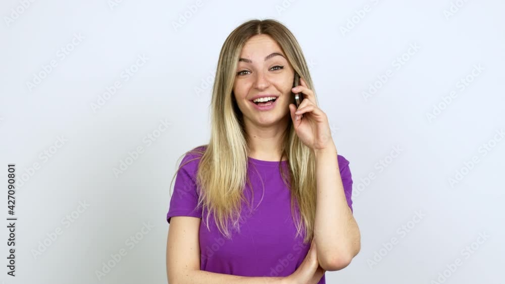 Young woman talking on mobile phone keeping the arms crossed while smiling over isolated background Young woman talking on mobile phone keeping the arms crossed while smiling over isolated background