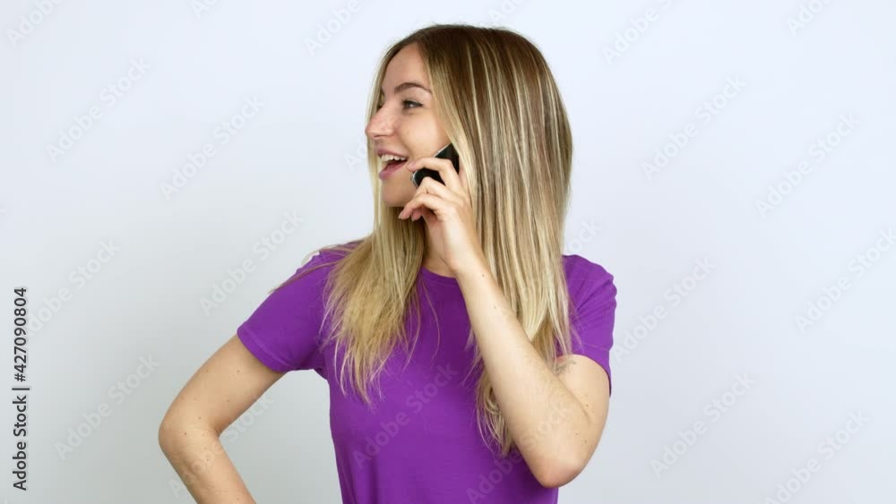 Young woman talking on mobile phone posing with arms at hip and laughing over isolated background Young woman talking on mobile phone posing with arms at hip and laughing over isolated background