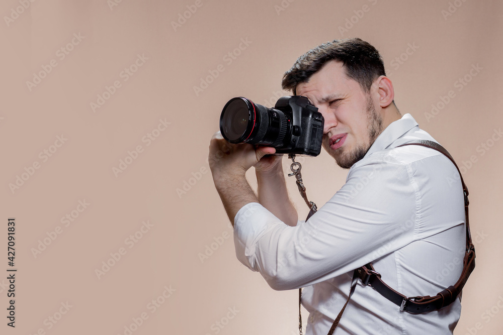 Portrait of concentrated person making photo looking wearing white shirt over brown background