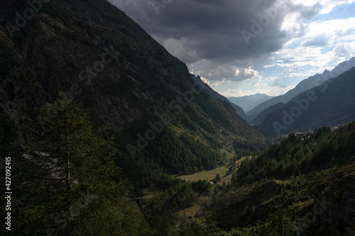 View of the valley from Place-Moulin, in the municipality of Bionaz in Valpelline. Mountains, trees, cloudy sky.